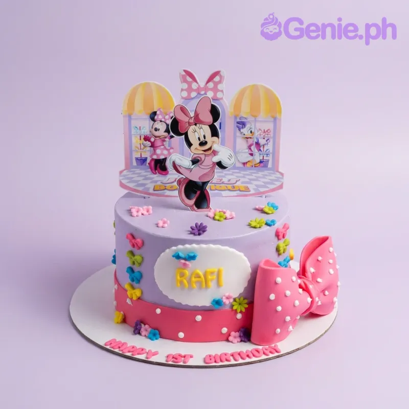 A purple 1 Tier cake themed around Minnie Mouse, featuring a Minnie Mouse and Daisy Duck printout, a pink bow, and colorful flowers. A purple 1 Tier cake themed around Minnie Mouse, featuring a Minnie Mouse and Daisy Duck printout, a pink bow, and colorful flowers.
