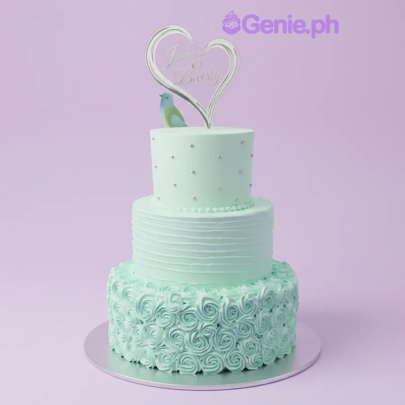 A mint green and silver three-tier cake themed around a wedding, featuring a heart-shaped topper, silver pearls, horizontal ridges, and icing rosettes. A mint green and silver three-tier cake themed around a wedding, featuring a heart-shaped topper, silver pearls, horizontal ridges, and icing rosettes.