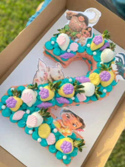 Teal number two cake with Moana character printouts, chocolate covered strawberries, and fondant seashells Teal number two cake with Moana character printouts, chocolate covered strawberries, and fondant seashells