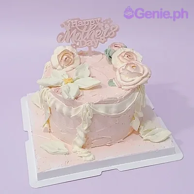 A light pink 1-tier Mother's Day cake, featuring a "Happy Mother's Day" topper, piped roses, and white icing ruffles. A light pink 1-tier Mother's Day cake, featuring a "Happy Mother's Day" topper, piped roses, and white icing ruffles.