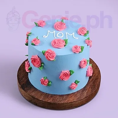 Light blue minimalist cake decorated with pink piped icing roses and green leaves with a white icing message saying MOM on top. Light blue minimalist cake decorated with pink piped icing roses and green leaves with a white icing message saying MOM on top.