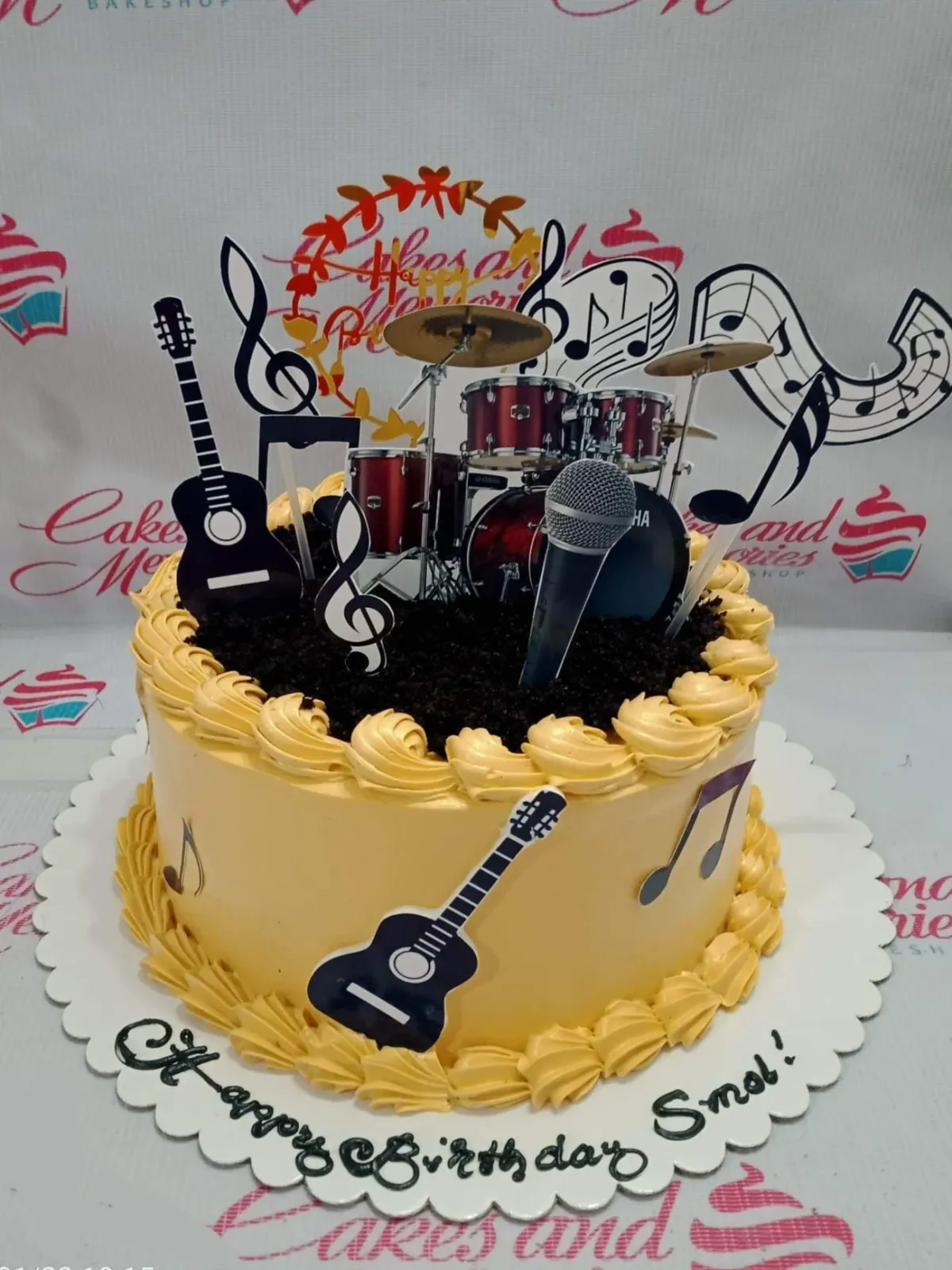 A yellow and black 1-Tier Music cake, featuring drum set, guitar, microphone, and 'Happy Birthday' banner, with cookie crumbs. A yellow and black 1-Tier Music cake, featuring drum set, guitar, microphone, and 'Happy Birthday' banner, with cookie crumbs.