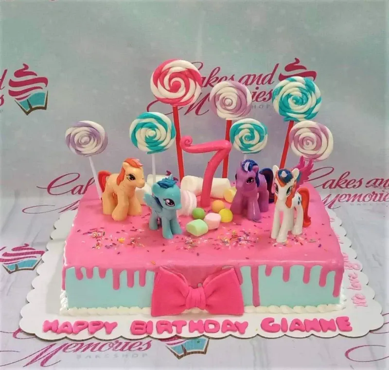 Rectangle My Little Pony birthday cake with pink and light blue icing, fondant ponies, lollipops, and a pink number 7 topper. Rectangle My Little Pony birthday cake with pink and light blue icing, fondant ponies, lollipops, and a pink number 7 topper.