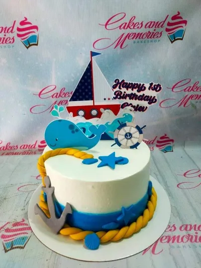 A white, blue, and yellow 1-tier cake themed Nautical, featuring a sailboat, whale, ship's wheel, and anchor. A white, blue, and yellow 1-tier cake themed Nautical, featuring a sailboat, whale, ship's wheel, and anchor.