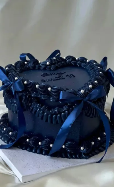 Navy single tier cake with smooth soft icing, navy satin ribbon bows, and white sugar pearl scatter