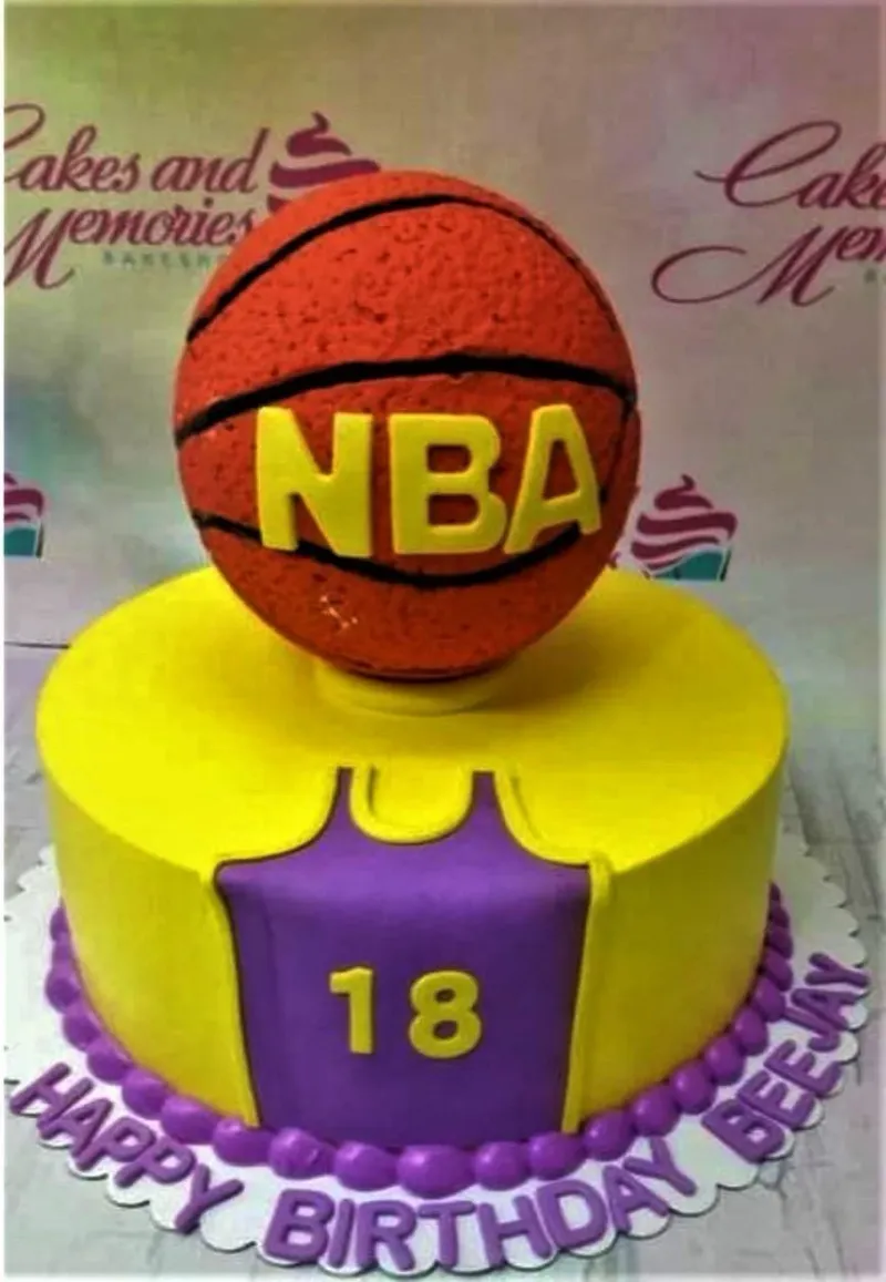 Yellow and purple NBA basketball themed birthday cake with a large 3D basketball topper and jersey design. Yellow and purple NBA basketball themed birthday cake with a large 3D basketball topper and jersey design.