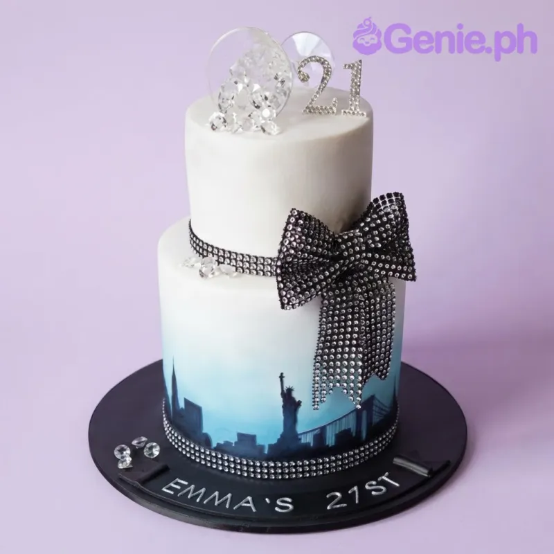 Sky blue and white 2-tier cake with soft gradient icing, a New York cityscape silhouette wrap, and a champagne glass topper Sky blue and white 2-tier cake with soft gradient icing, a New York cityscape silhouette wrap, and a champagne glass topper