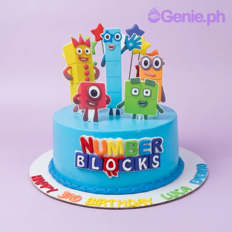 A light blue 1 Tier cake themed around Numberblocks, featuring character printouts, a colorful logo, and red gumpaste letters. A light blue 1 Tier cake themed around Numberblocks, featuring character printouts, a colorful logo, and red gumpaste letters.