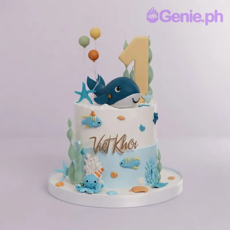 White and light blue 1-tier birthday cake with a whale topper, yellow number one, and sea creature decorations White and light blue 1-tier birthday cake with a whale topper, yellow number one, and sea creature decorations