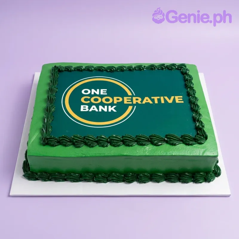 A green rectangular cake themed around One Cooperative Bank, featuring a large One Cooperative Bank logo printout and dark green piped icing rosettes. A green rectangular cake themed around One Cooperative Bank, featuring a large One Cooperative Bank logo printout and dark green piped icing rosettes.