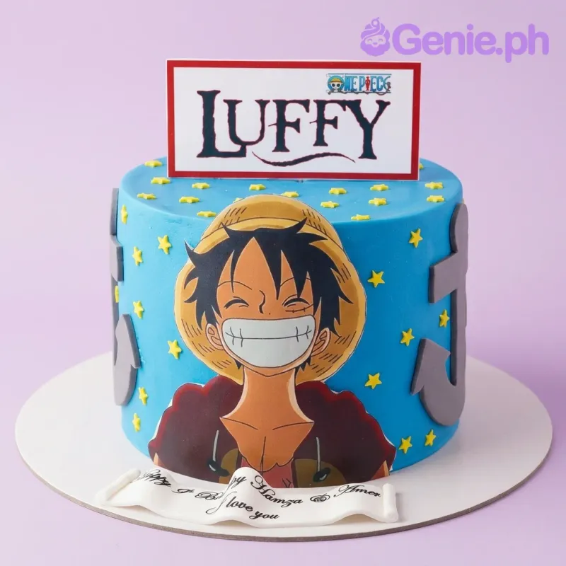 A blue 1-tier fondant cake themed around One Piece Luffy, featuring a Monkey D. Luffy cutout, a Luffy name sign, a grey anchor, and yellow stars. A blue 1-tier fondant cake themed around One Piece Luffy, featuring a Monkey D. Luffy cutout, a Luffy name sign, a grey anchor, and yellow stars.