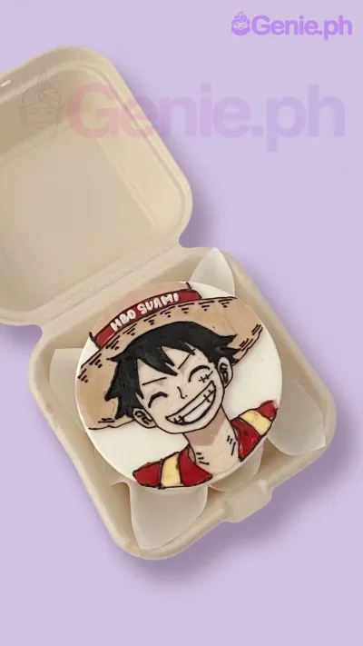 A white Bento cake themed around One Piece Luffy, featuring a hand-piped illustration of Monkey D. Luffy and a red banner with 'HBD SUAMI' text. A white Bento cake themed around One Piece Luffy, featuring a hand-piped illustration of Monkey D. Luffy and a red banner with 'HBD SUAMI' text.