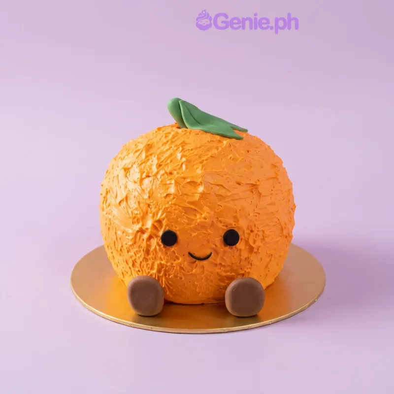 Orange-shaped 1-tier cake with green leaf, black eyes, and brown feet on a gold board Orange-shaped 1-tier cake with green leaf, black eyes, and brown feet on a gold board