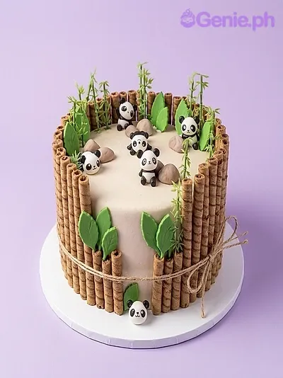 Panda green cake design — 1 layer soft icing cake in white — with small panda figures, wafer rolls, green leaves, and edible rocks Panda green cake design — 1 layer soft icing cake in white — with small panda figures, wafer rolls, green leaves, and edible rocks