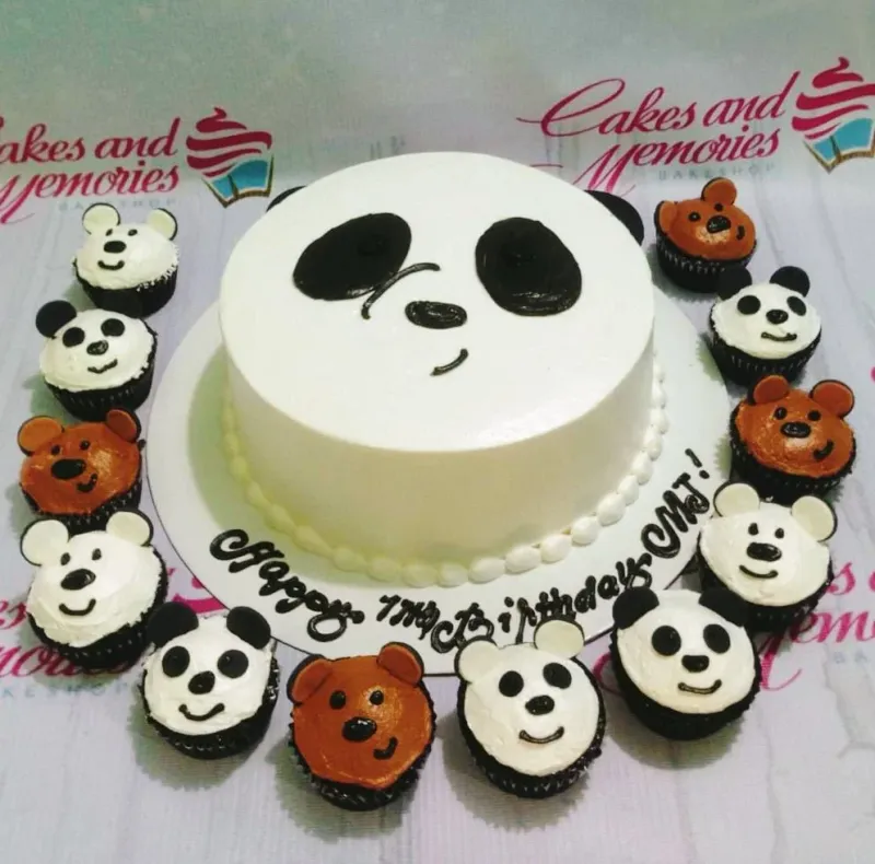 White round cake with a panda face design and matching panda and bear cupcakes arranged around the base. White round cake with a panda face design and matching panda and bear cupcakes arranged around the base.