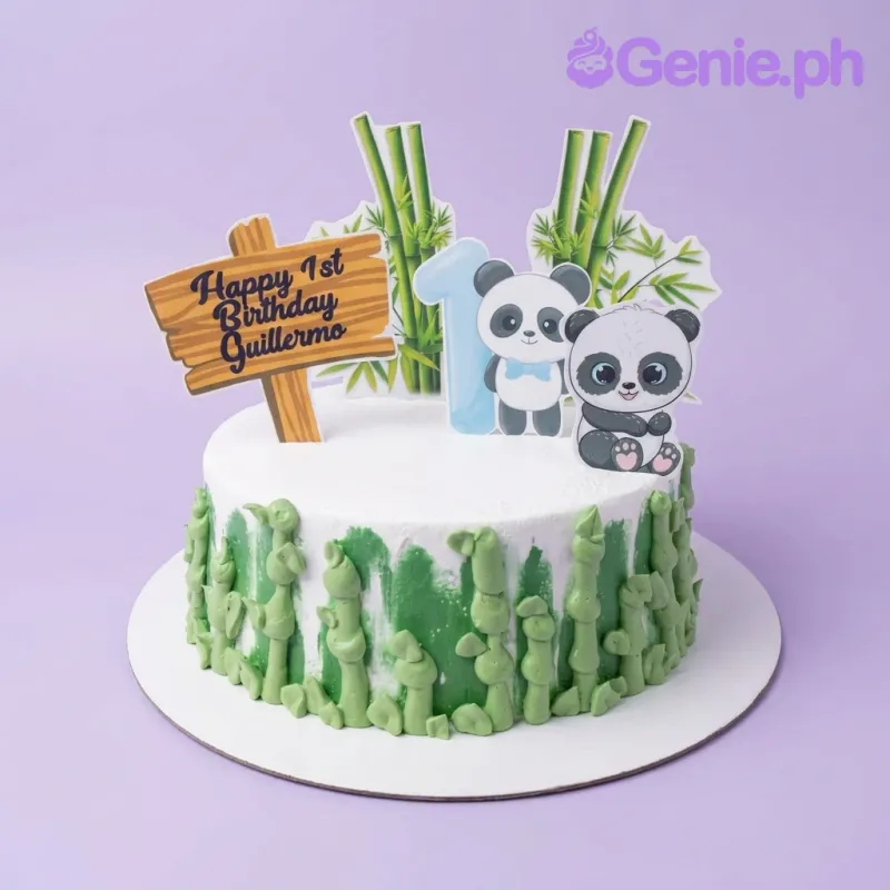 A white and green 1-tier cake themed around Panda, featuring panda and number one toppers, and green piped bamboo stalks. A white and green 1-tier cake themed around Panda, featuring panda and number one toppers, and green piped bamboo stalks.
