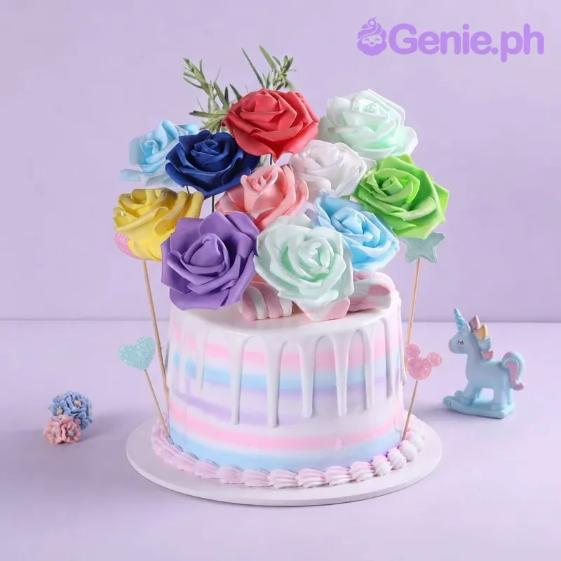 Pastel blue, pink, and white 1-tier cake with white drip icing, colorful stripes, and an arrangement of colorful edible rose flowers on top Pastel blue, pink, and white 1-tier cake with white drip icing, colorful stripes, and an arrangement of colorful edible rose flowers on top
