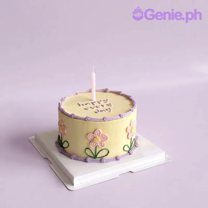 Pale yellow 1-tier cake with soft icing, pastel floral theme, piped purple borders, and a pink spiral candle Pale yellow 1-tier cake with soft icing, pastel floral theme, piped purple borders, and a pink spiral candle