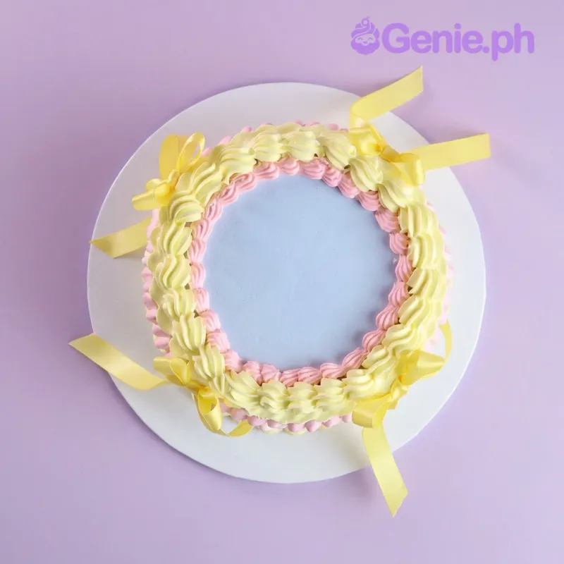 Light blue round cake with pink and yellow piped borders and yellow satin ribbon accents on a light blue plate Light blue round cake with pink and yellow piped borders and yellow satin ribbon accents on a light blue plate