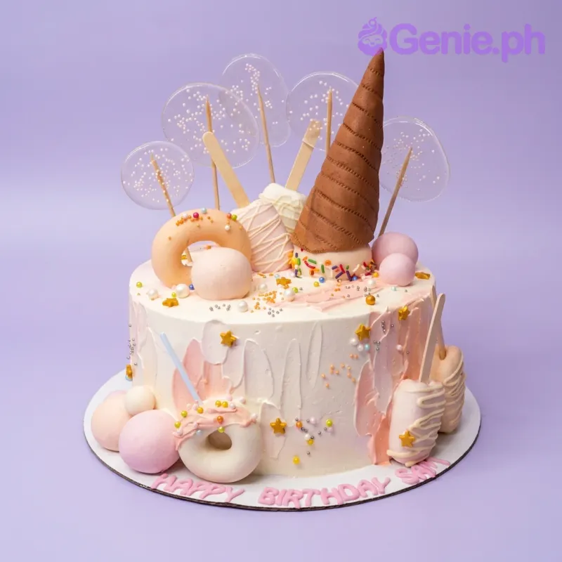 White 1-tier birthday cake with a large brown waffle cone topper, pastel donuts, popsicles, and clear isomalt lollipops with sprinkles. White 1-tier birthday cake with a large brown waffle cone topper, pastel donuts, popsicles, and clear isomalt lollipops with sprinkles.