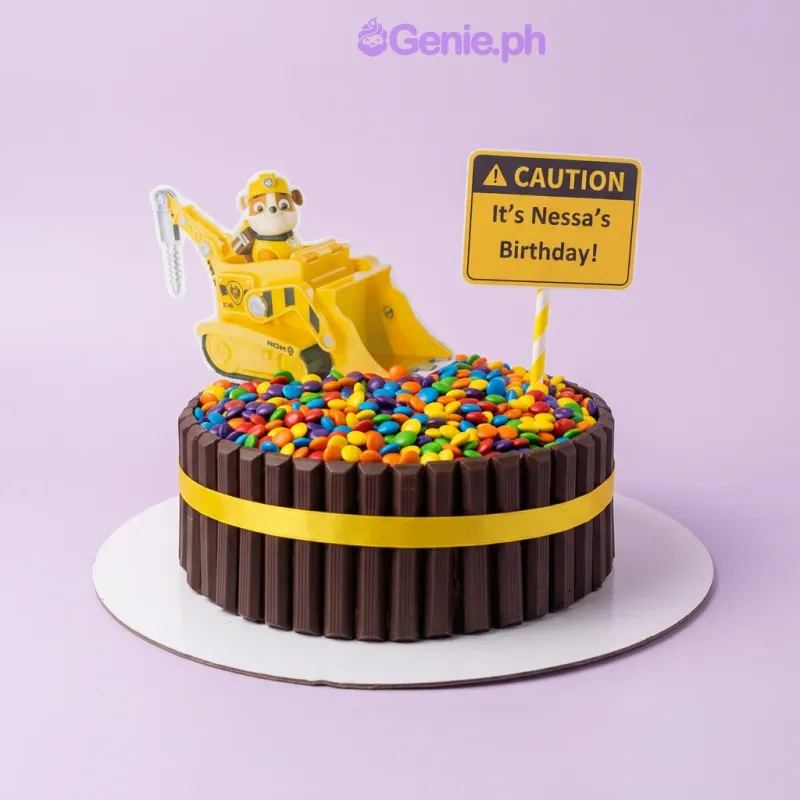 A black 1-tier Paw Patrol Construction cake with Rubble, a caution sign, KitKat border, and M&M topping. A black 1-tier Paw Patrol Construction cake with Rubble, a caution sign, KitKat border, and M&M topping.