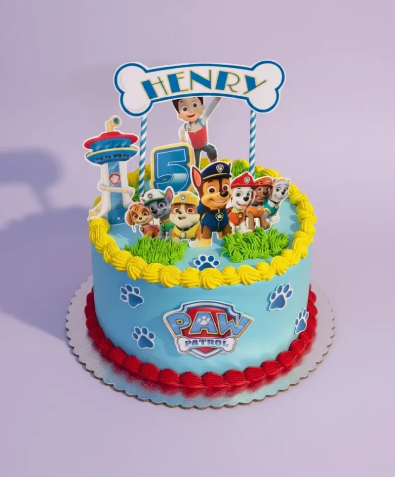 A blue 1-tier Paw Patrol cake, featuring character and number printouts, with yellow icing borders. A blue 1-tier Paw Patrol cake, featuring character and number printouts, with yellow icing borders.