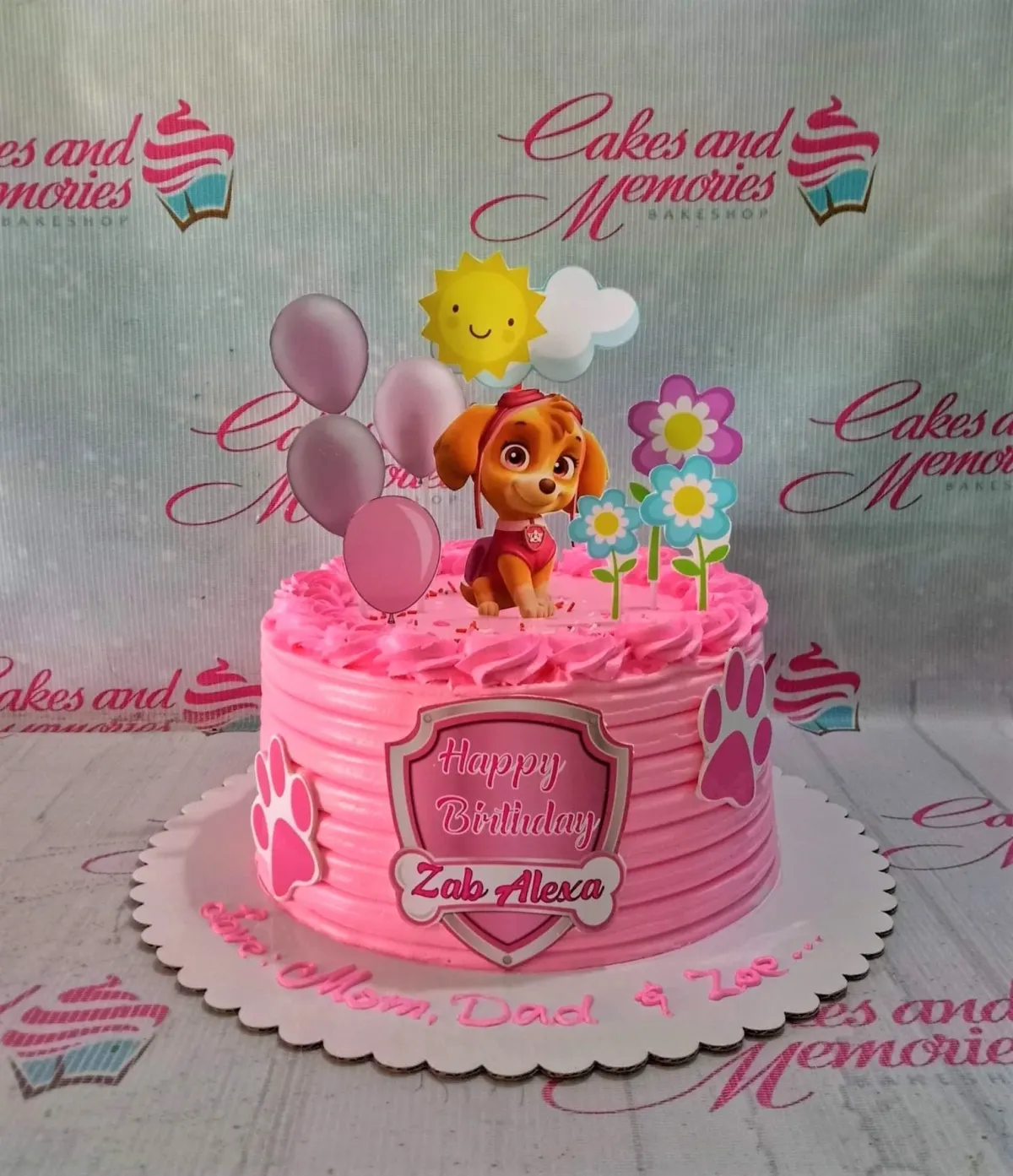 A pink 1 Tier cake themed around Paw Patrol Skye, featuring a Skye character, birthday shield, sun, clouds, flowers, and paw print cutouts. A pink 1 Tier cake themed around Paw Patrol Skye, featuring a Skye character, birthday shield, sun, clouds, flowers, and paw print cutouts.