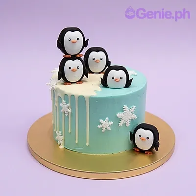 Light blue 1-tier cake with white drip and three penguin fondant toppers and white snowflake decorations Light blue 1-tier cake with white drip and three penguin fondant toppers and white snowflake decorations