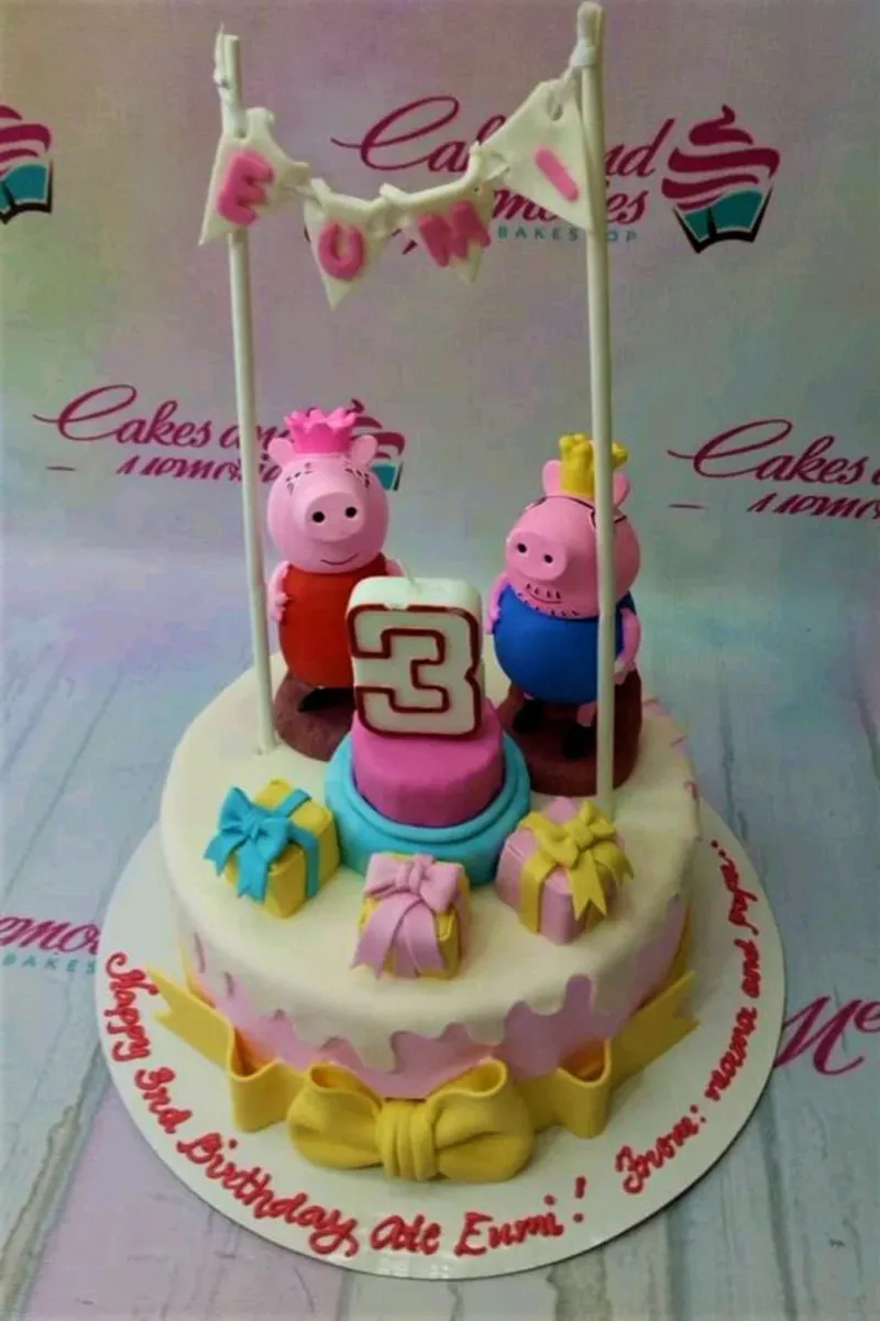 A white and pink 1-tier fondant cake themed around Peppa Pig, featuring 3D Peppa and George figures, a name banner, and a number 3 candle. A white and pink 1-tier fondant cake themed around Peppa Pig, featuring 3D Peppa and George figures, a name banner, and a number 3 candle.