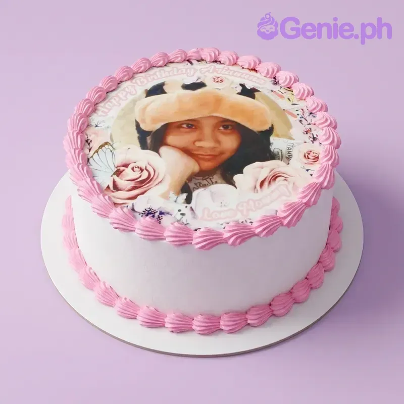 A white round Photo Birthday cake with pink icing borders, an edible photo, and butterfly and rose accents. A white round Photo Birthday cake with pink icing borders, an edible photo, and butterfly and rose accents.
