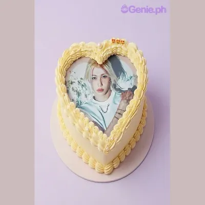 Light yellow heart-shaped cake with a photo print of a person on top and a piped border Light yellow heart-shaped cake with a photo print of a person on top and a piped border
