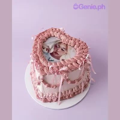 Light pink heart-shaped cake with a photo print on top and small pink bows on the sides Light pink heart-shaped cake with a photo print on top and small pink bows on the sides