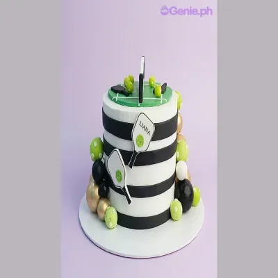 White single tier cake with black horizontal stripes and pickleball paddle printouts White single tier cake with black horizontal stripes and pickleball paddle printouts