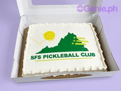 A white rectangle sheet cake themed around Pickleball, featuring an SFS Pickleball Club logo printout and white piped icing borders. A white rectangle sheet cake themed around Pickleball, featuring an SFS Pickleball Club logo printout and white piped icing borders.