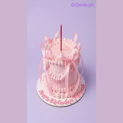 Pink 1-tier birthday cake with satin ribbons and a lit candle Pink 1-tier birthday cake with satin ribbons and a lit candle