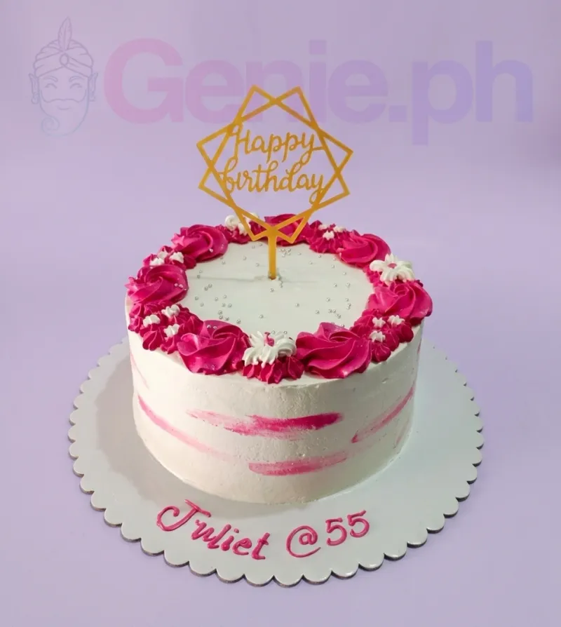 A white round 1-tier cake with pink icing rosettes, silver dragees, a gold 'Happy Birthday' topper, and an icing message. A white round 1-tier cake with pink icing rosettes, silver dragees, a gold 'Happy Birthday' topper, and an icing message.