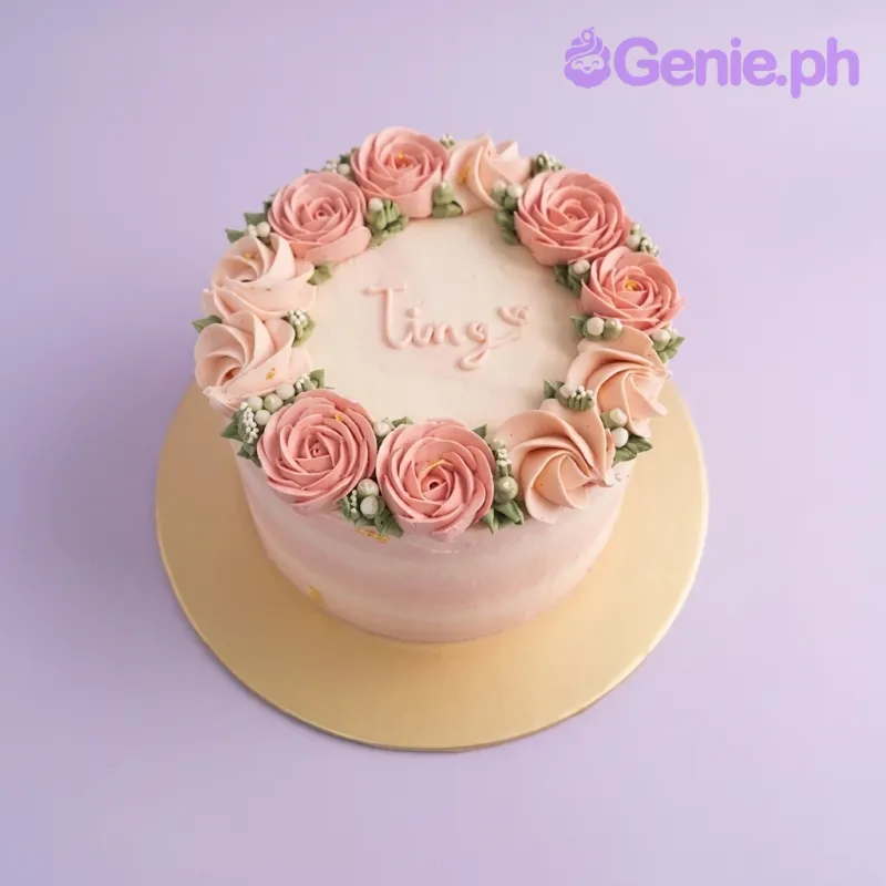 A pink and white ombre single tier floral cake featuring pink and peach rosettes, green leaves, white pearls, and a personalized message. A pink and white ombre single tier floral cake featuring pink and peach rosettes, green leaves, white pearls, and a personalized message.