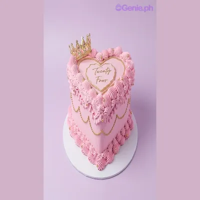 Single tier cake with pink soft icing, a gold crown topper, gold beads, piped gold chain, and a piped border with text on top Single tier cake with pink soft icing, a gold crown topper, gold beads, piped gold chain, and a piped border with text on top