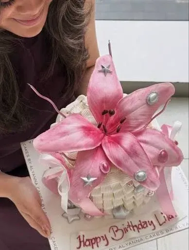 White 1 tier cake with smooth soft icing, giant pink lily fondant flower topper, and silver star accents White 1 tier cake with smooth soft icing, giant pink lily fondant flower topper, and silver star accents
