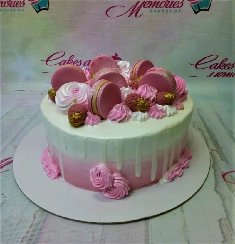 A pink and white ombre 1-tier cake featuring pink macarons, gold-dusted chocolate raspberries, and pink and white icing rosettes. A pink and white ombre 1-tier cake featuring pink macarons, gold-dusted chocolate raspberries, and pink and white icing rosettes.