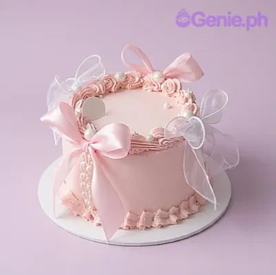 Light pink 1-tier cake with soft icing, a large sheer organza bow, piped rosettes, and pearl accents Light pink 1-tier cake with soft icing, a large sheer organza bow, piped rosettes, and pearl accents
