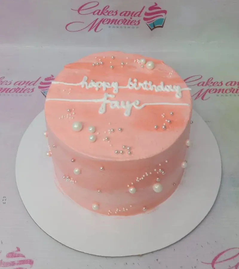 A pink and white 1-tier cake themed around minimalist birthday, featuring white icing text and silver and white pearl sprinkles. A pink and white 1-tier cake themed around minimalist birthday, featuring white icing text and silver and white pearl sprinkles.