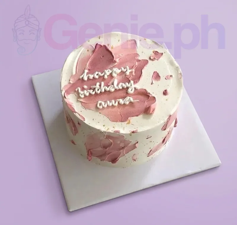 A white and pink Minimalist 1 Tier cake, featuring pink palette knife strokes, gold speckles, and a white piped message. A white and pink Minimalist 1 Tier cake, featuring pink palette knife strokes, gold speckles, and a white piped message.