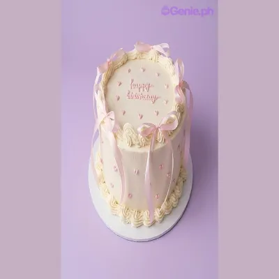 White single-tier birthday cake with pink satin ribbons and piped pink hearts White single-tier birthday cake with pink satin ribbons and piped pink hearts
