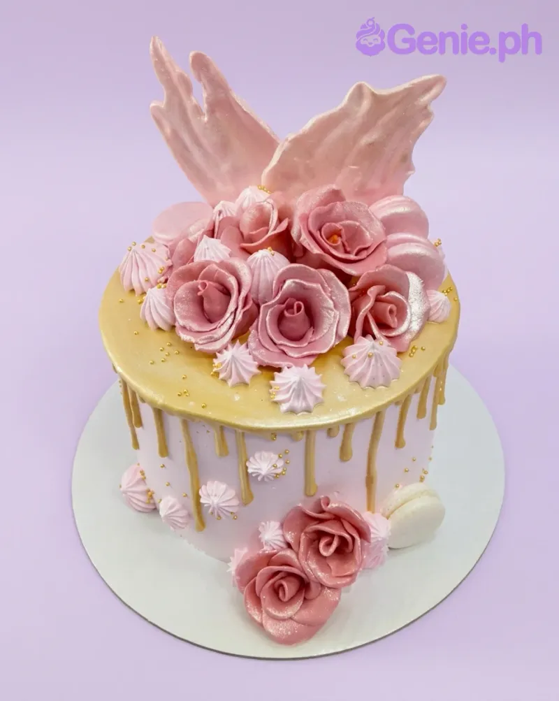 A pink and gold 1-tier Rose Gold Drip cake, featuring pink gumpaste wings, fondant roses, and meringue kisses. A pink and gold 1-tier Rose Gold Drip cake, featuring pink gumpaste wings, fondant roses, and meringue kisses.
