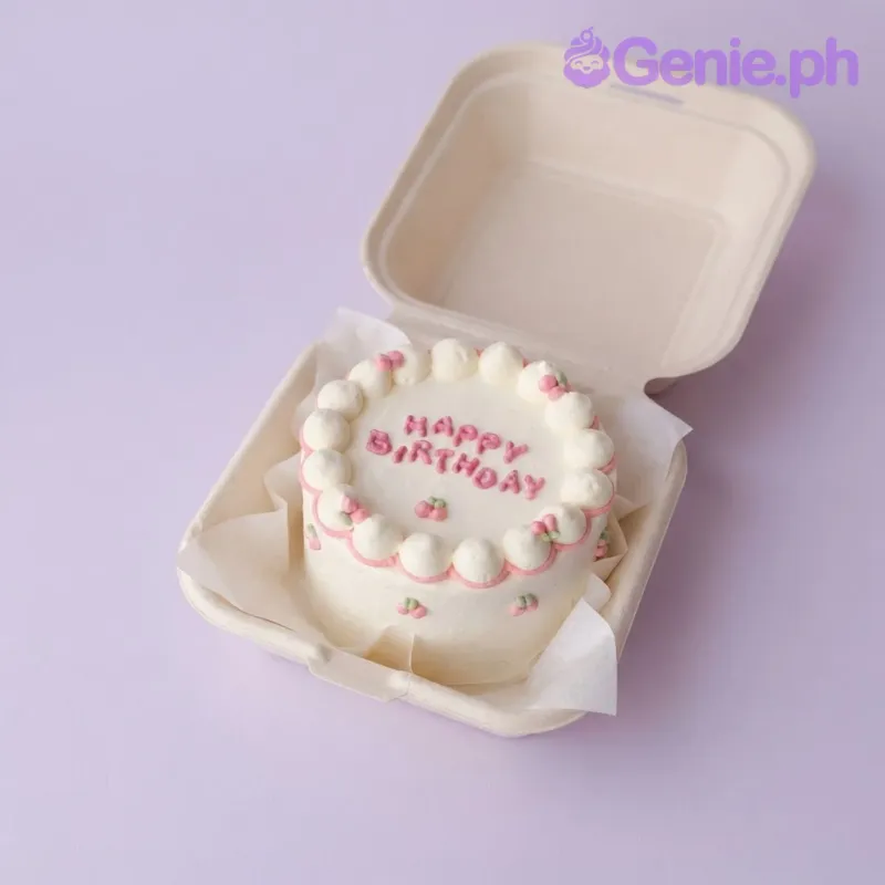 Ivory bento cake with soft icing, a piped white shell border, and pink piped flower sprigs