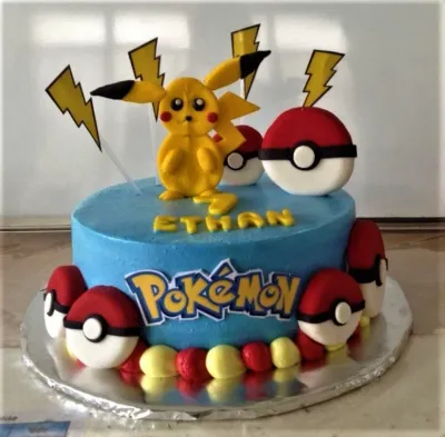 A blue, yellow, red, and white 1-tier cake themed around Pokemon Pikachu, featuring a 3D Pikachu figure, Pokeballs, and yellow lightning bolts. A blue, yellow, red, and white 1-tier cake themed around Pokemon Pikachu, featuring a 3D Pikachu figure, Pokeballs, and yellow lightning bolts.