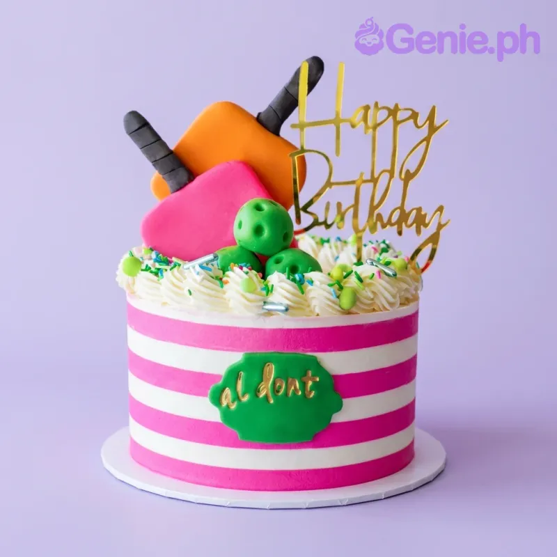 A pink and white striped 1-tier cake, Popsicle Birthday themed, with popsicles, green bowling balls, and a gold 'Happy Birthday' topper. A pink and white striped 1-tier cake, Popsicle Birthday themed, with popsicles, green bowling balls, and a gold 'Happy Birthday' topper.