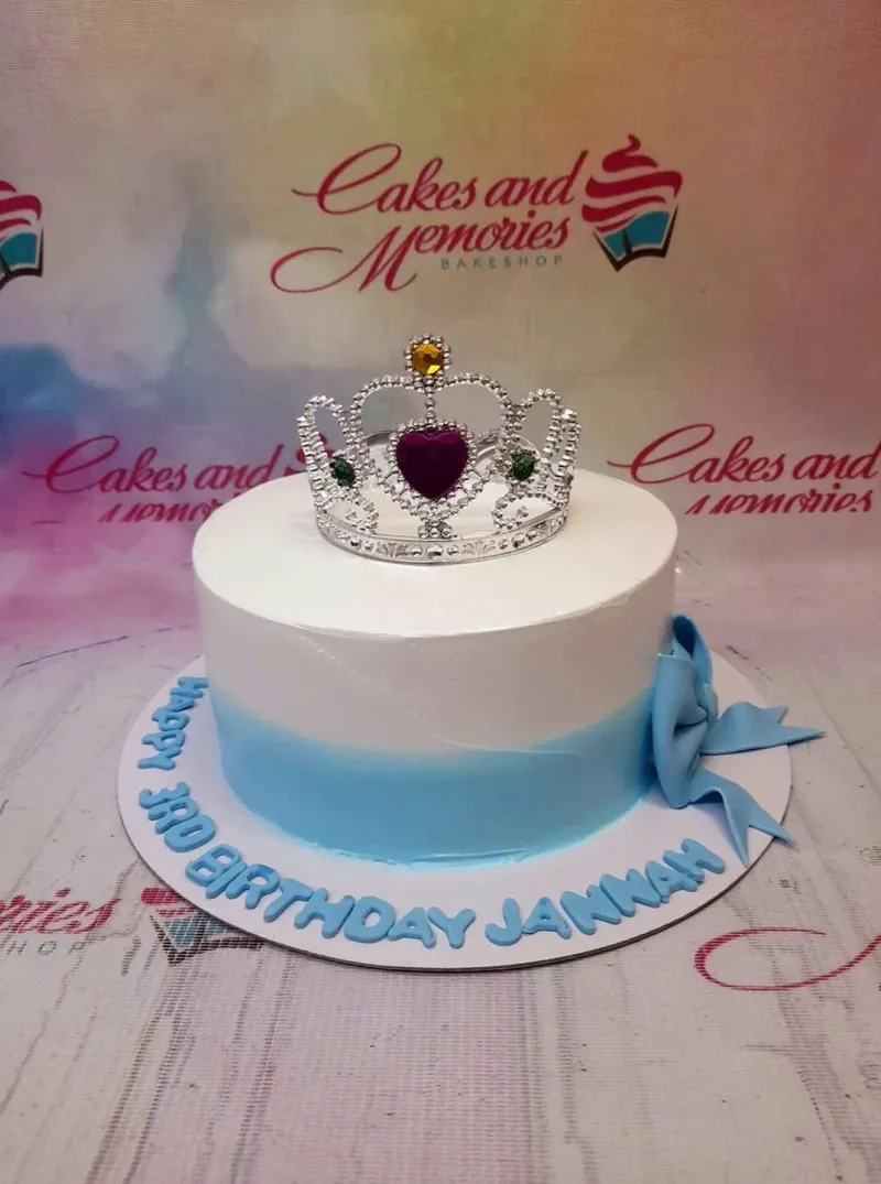 White and light blue gradient cake with a silver rhinestone tiara and a blue fondant bow on the side. White and light blue gradient cake with a silver rhinestone tiara and a blue fondant bow on the side.