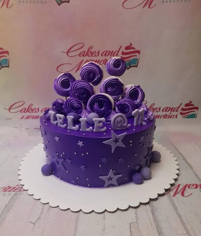 A purple 1-tier birthday cake with purple meringue pops, light purple stars, silver dragees, and 'LELLE @ 11' text. A purple 1-tier birthday cake with purple meringue pops, light purple stars, silver dragees, and 'LELLE @ 11' text.